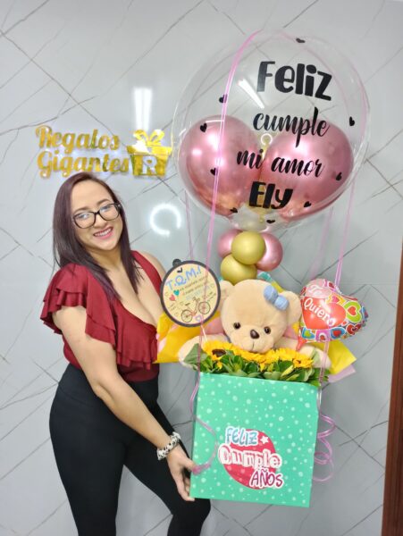 Oso de peluche gigante de color café sentado junto a una persona para mostrar su gran tamaño.